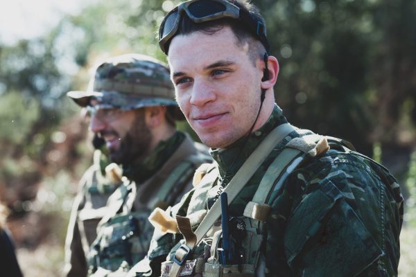 Airsoft military game player in camouflage uniform with armed assault rifle.