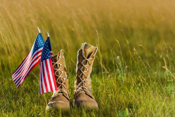 military boots near american flag with stars and stripes on grass